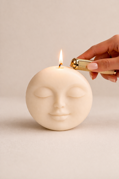 Cream moon face candle being lit with a gold lighter – Pretty Moon Candle by THE AURA CO.