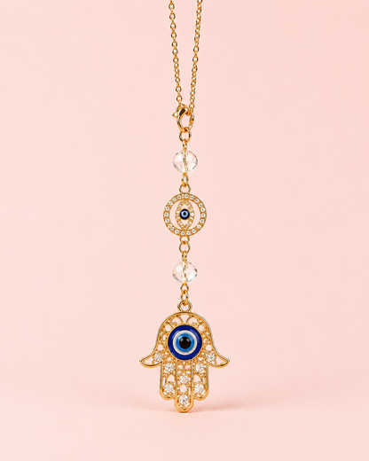Gold celestial eye and crescent moon sun catcher with cascading crystal prism and star bead chains on a blush pink background – THE AURA CO.