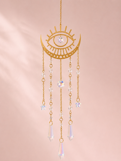Gold celestial eye and crescent moon sun catcher with cascading crystal prism and star bead chains on a blush pink background – THE AURA CO.