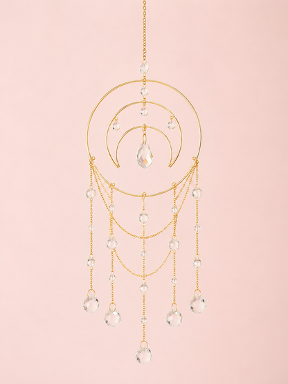 Gold ring crescent moon sun catcher with cascading faceted glass bead chains on a blush pink background – THE AURA CO.